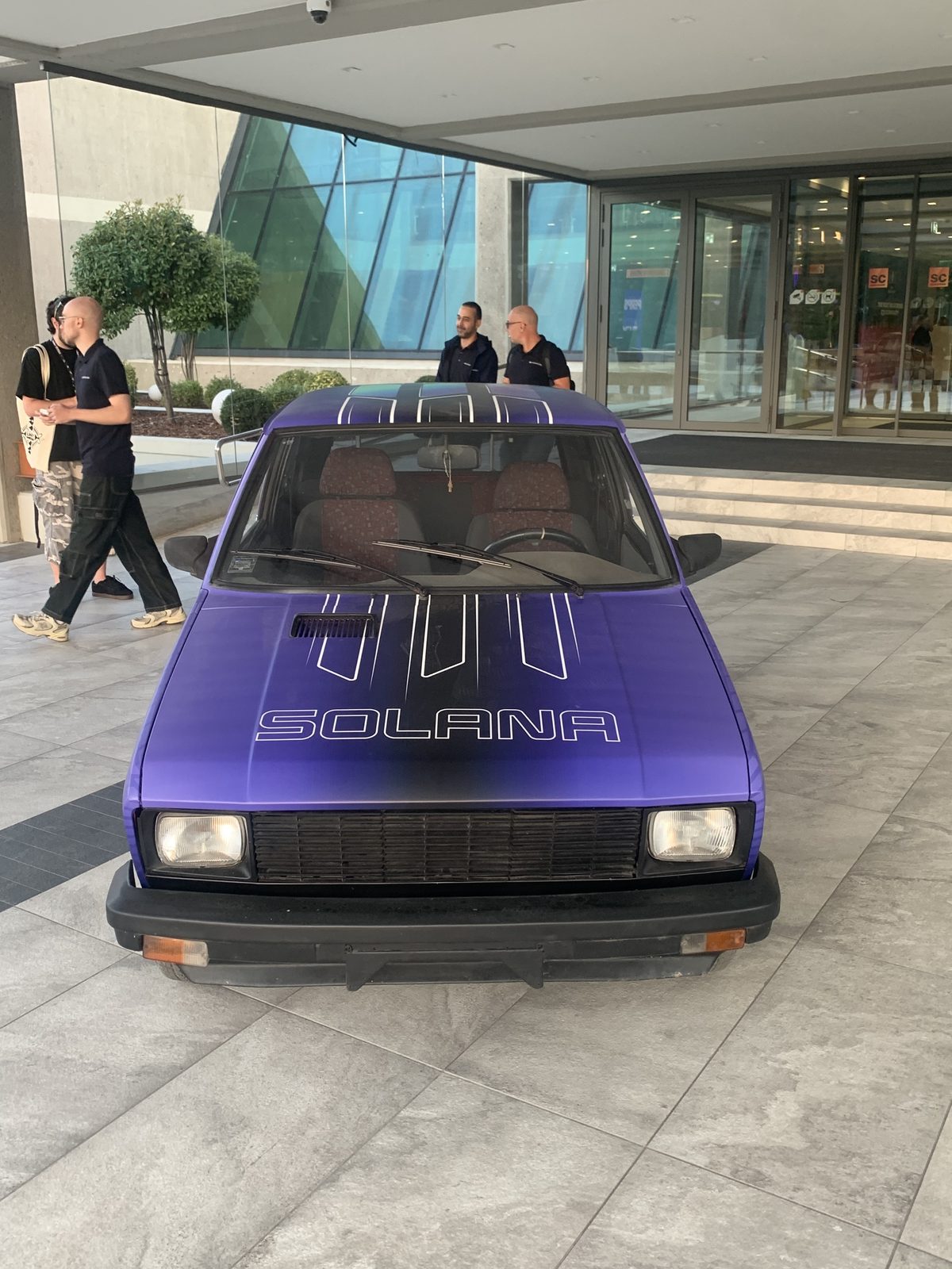 Yugo car wrapped in purple Solana livery parked at the entrance of the Sava Center during Solana Summit Serbia
